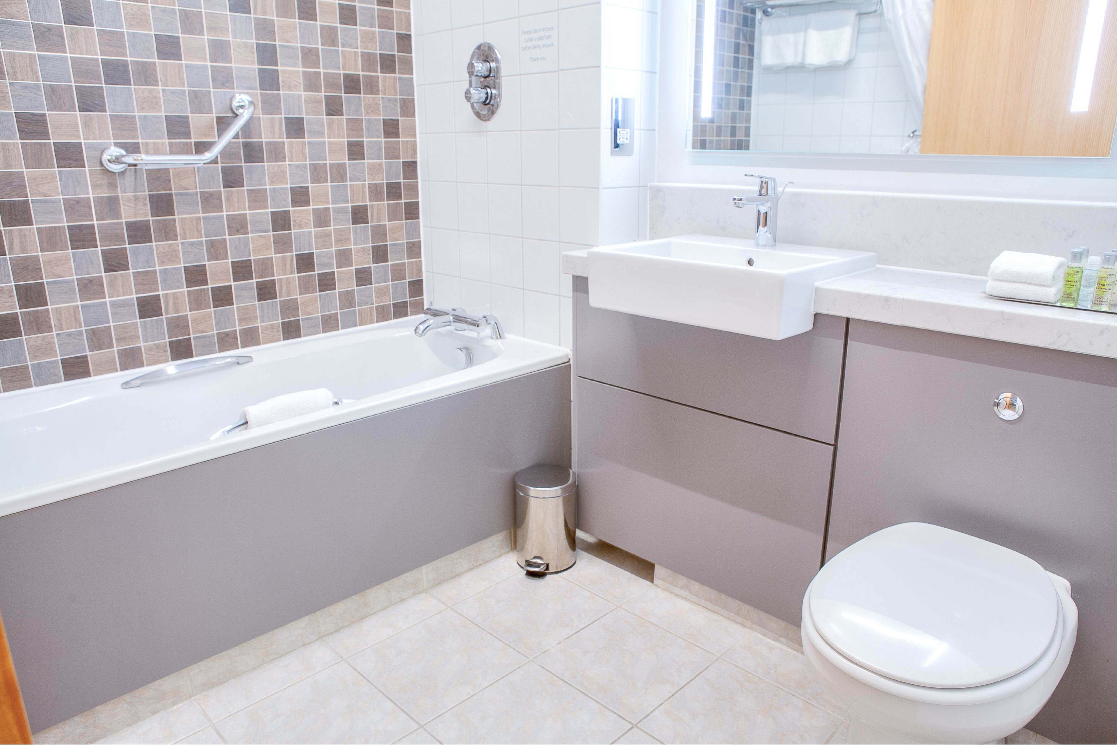 A modern bathroom with a bathtub, sink, and toilet.