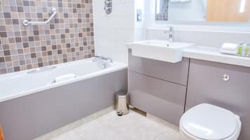 A modern bathroom with a bathtub, sink, and toilet.