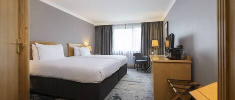 Een hotelkamer met een groot bed, een bureau met stoel, een bijzettafeltje en een spiegel.