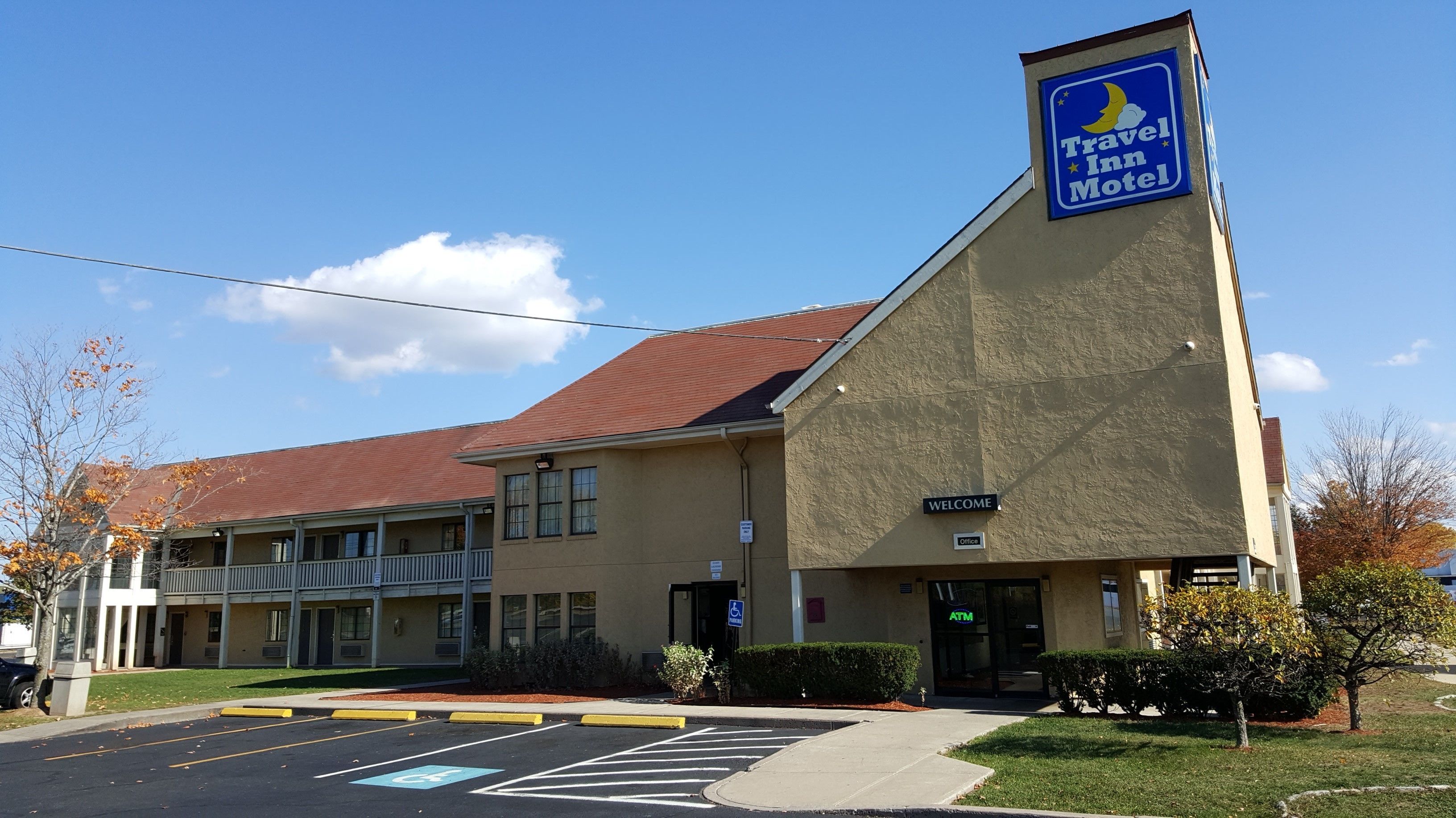 A Travel Inn Motel with a welcoming sign, accessible parking, and an ATM.