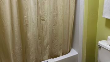 A bathroom with a bathtub, toilet, and a shower curtain.
