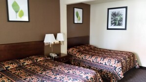 A hotel room with two beds, a nightstand with a lamp, and framed artwork on the walls. - Travel Inn Motel (Hartford)