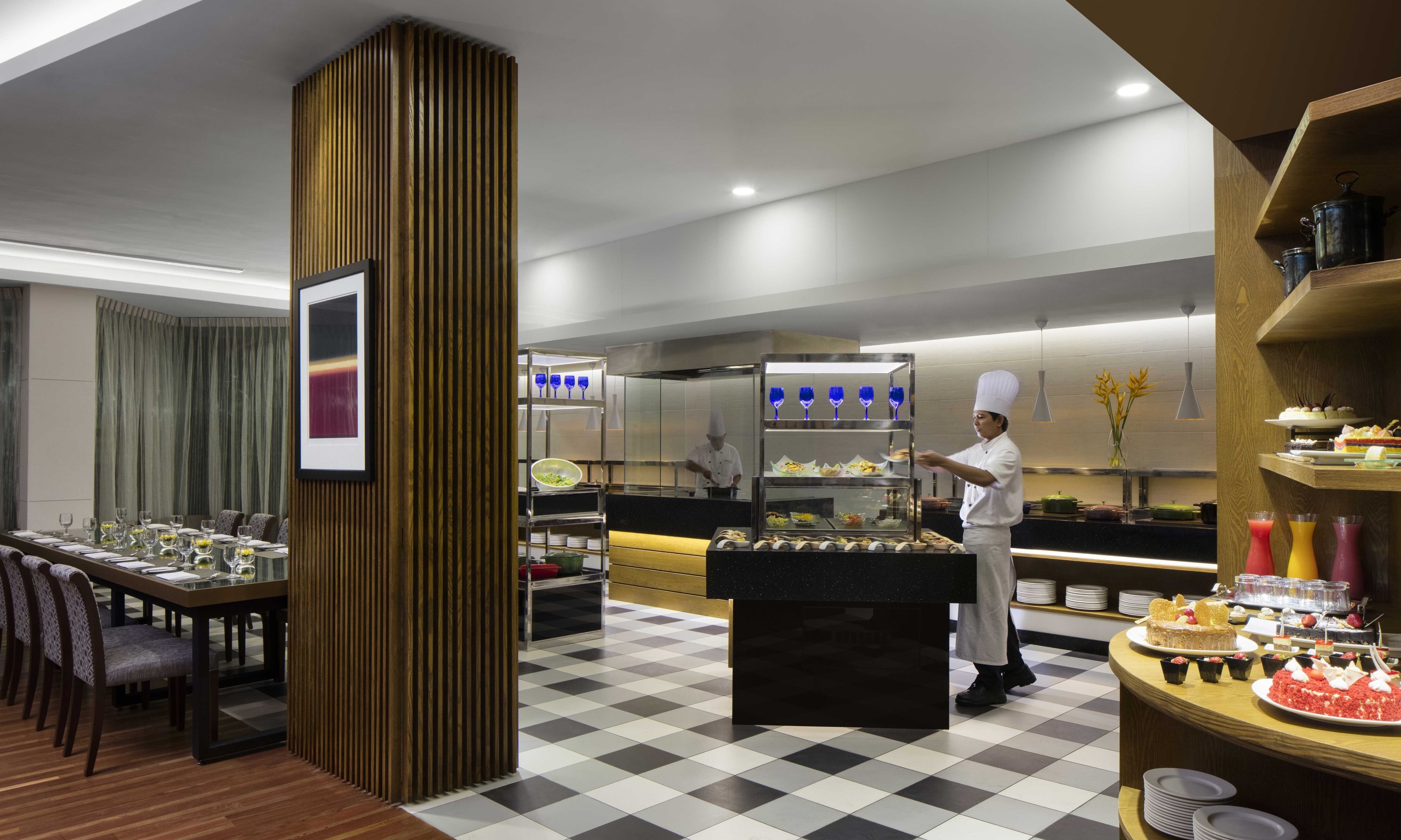 Un restaurante moderno con piso a cuadros, una columna central de madera y un chef preparando comida.