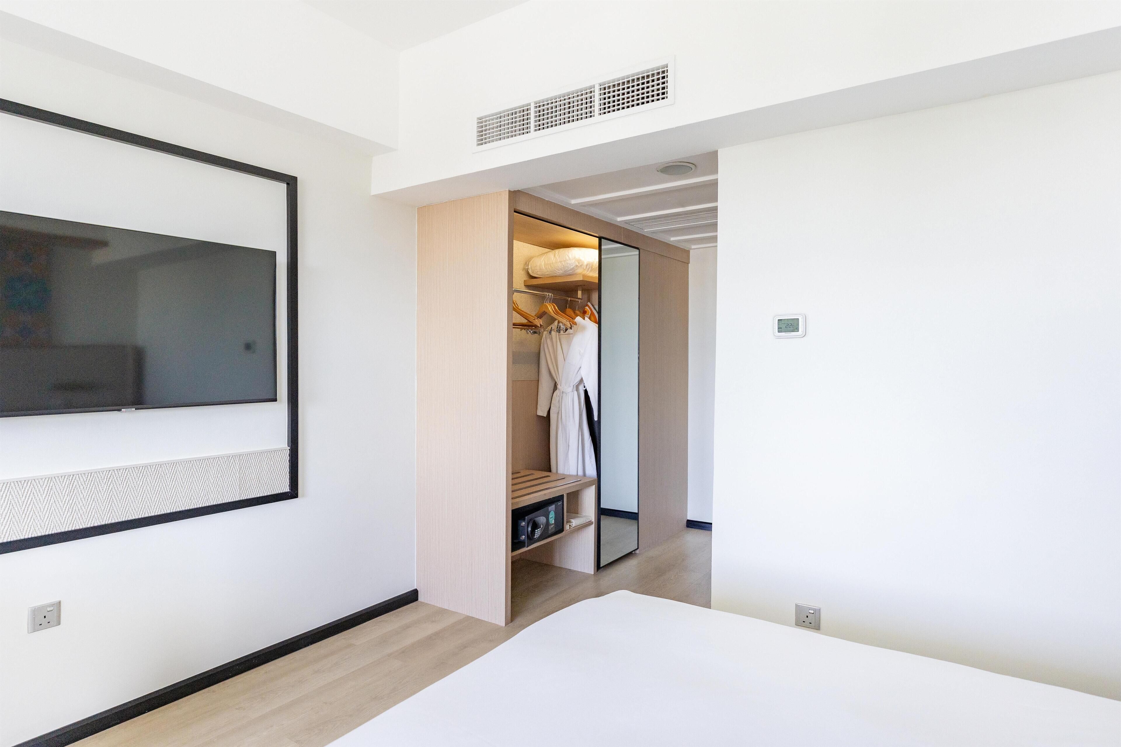 A modern bedroom with a large bed, a built-in wardrobe, and a mirror.
