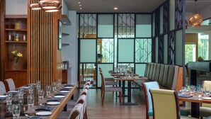 Un restaurante con una larga mesa de comedor dispuesta para una comida, paneles de madera y vistas a través de grandes ventanales.