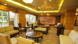 A spacious lobby with comfortable seating, a large wall art piece, and a reception desk. - Kapok Hotel (Port of Spain)