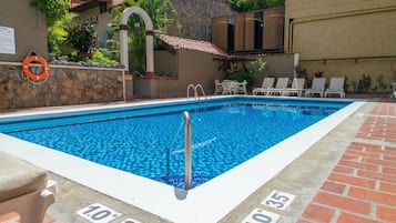 Una piscina al aire libre, sillones reclinables de piscina