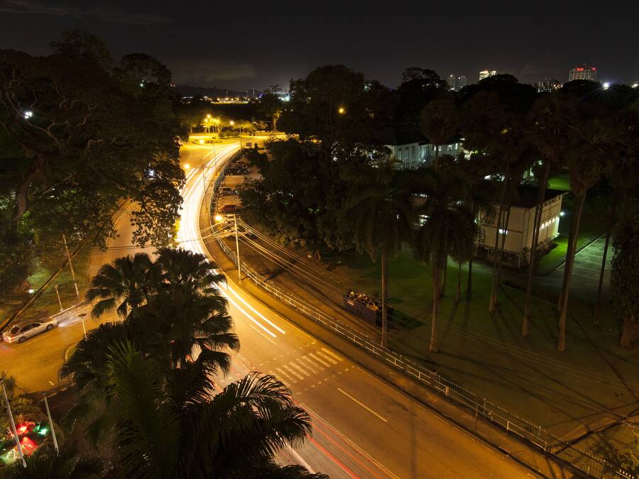 Vista aérea de una intersección urbana de noche, con semáforos y farolas visibles.