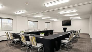 Un salón de conferencias con una larga mesa, sillas e iluminación en el techo.