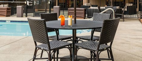 Um pátio externo com mesa de bilhar, cadeiras e guarda-sóis.