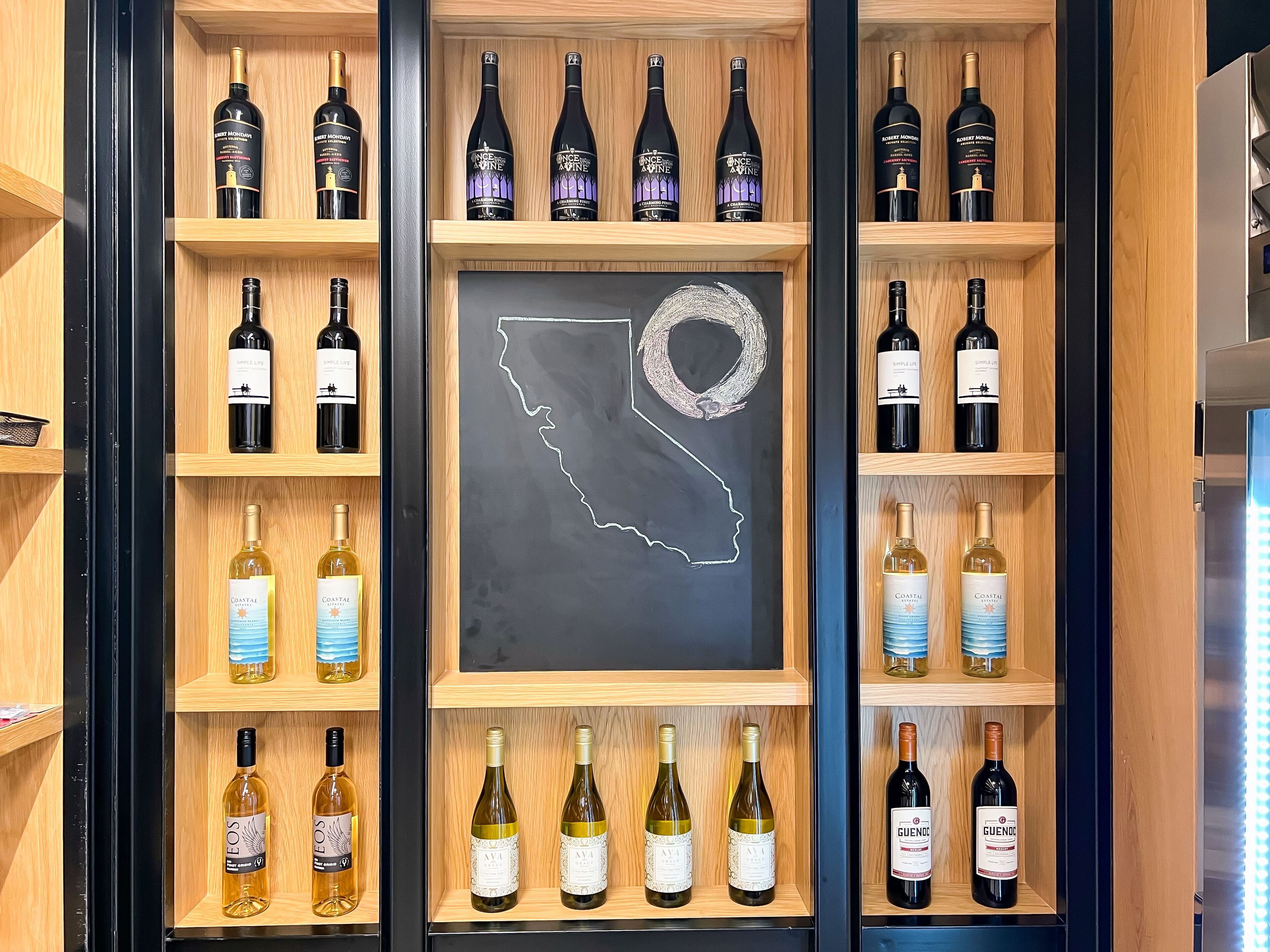 A wine rack with various bottles, a chalkboard with a map outline, and a refrigerator.