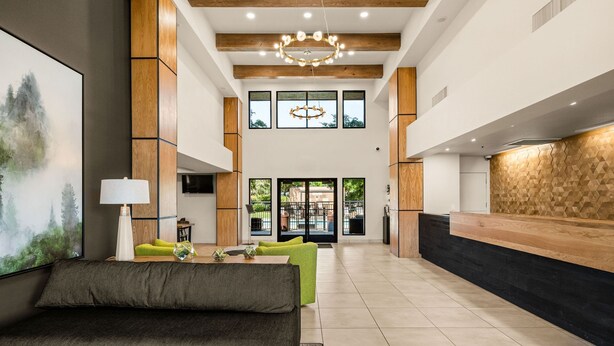 Un hall d’entrée spacieux au design moderne, comprenant un comptoir d’accueil, un espace salon et de grandes fenêtres laissant entrer la lumière naturelle.