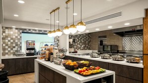 Une cuisine moderne dotée d’un îlot central, équipé de divers appareils et aménagé avec un buffet.