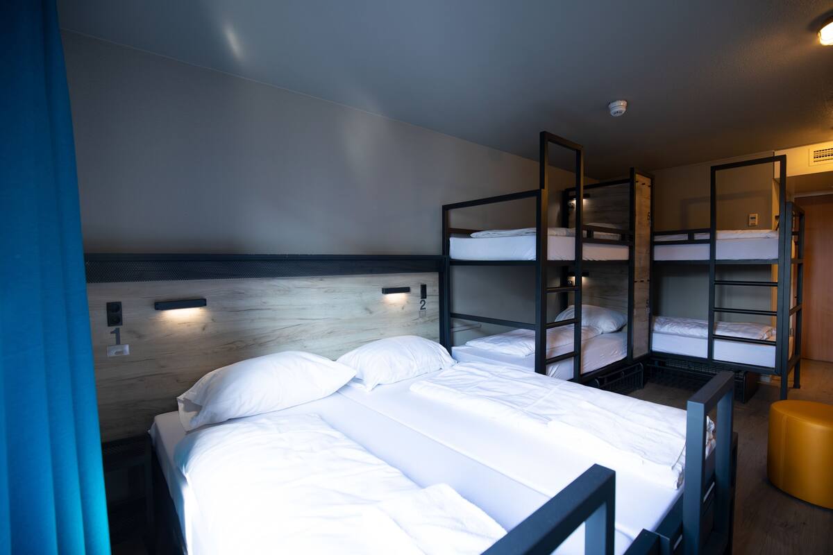 A room with bunk beds, a wooden headboard, and a small stool.