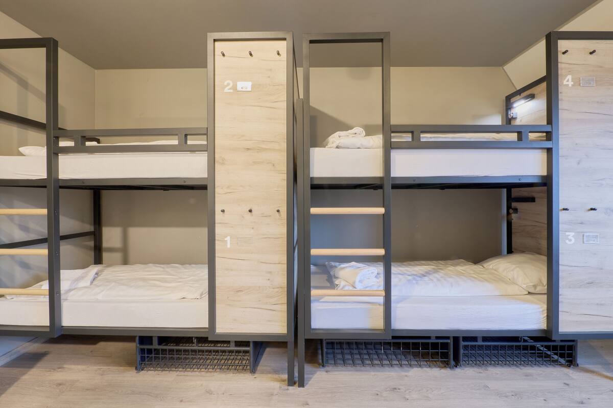 A bunk bed room with three levels, each with a wooden panel and metal frame.