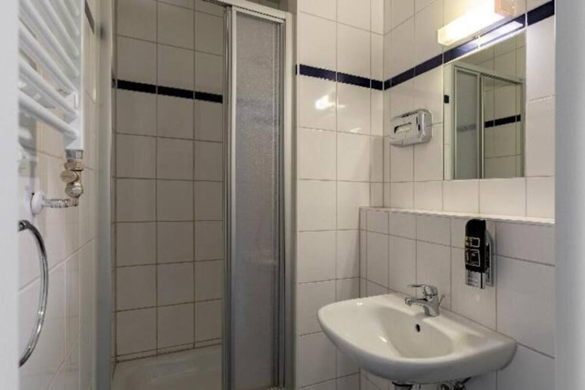 A bathroom with a shower, sink, and mirror.