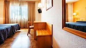 A hotel room with two beds, a desk, a chair, a TV, and a large mirror. - Hotel Alcarria (Guadalajara)