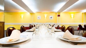 A conference room with a long table set for a meeting, equipped with chairs and tables, and a yellow wall with a clock and a sign. - Hotel Alcarria (Guadalajara)