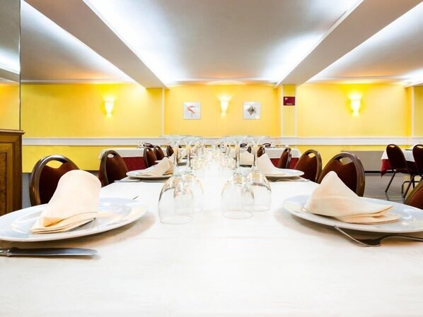 A conference room with a long table set for a meeting, equipped with chairs and tables, and a yellow wall with a clock and a sign. - Hotel Alcarria (Guadalajara)