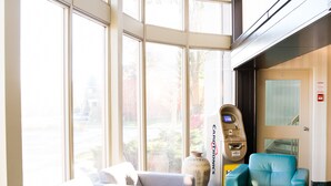 A lobby with large windows, seating areas, a card machine, and a door. - Admiral Inn Hamilton (Hamilton)