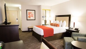 A hotel room with a bed, bedside table, lamp, chair, and a desk with a computer. - Admiral Inn Hamilton (Hamilton)