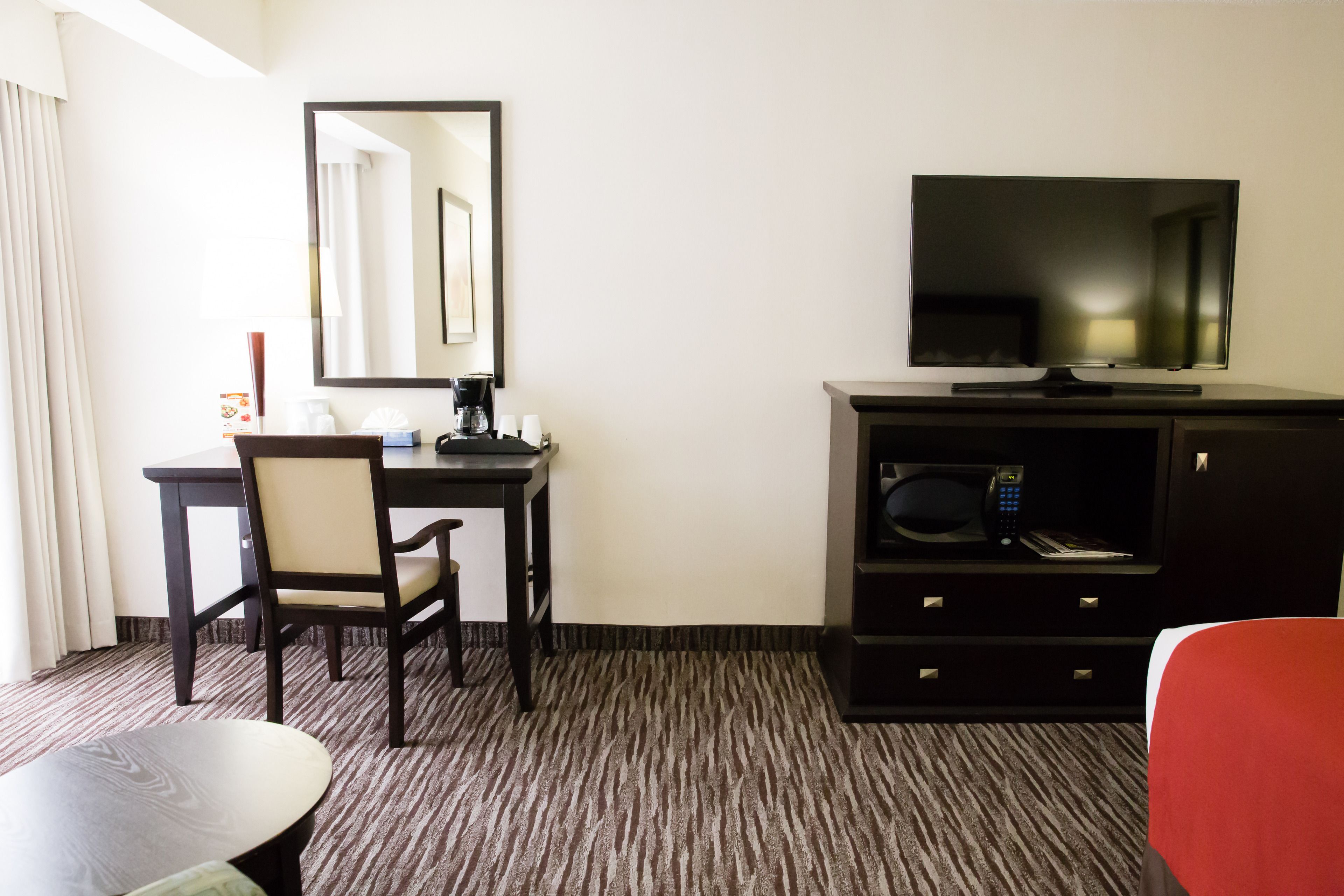 Une chambre d’hôtel équipée d’un bureau, d’une chaise, d’une télévision et d’une petite table.
