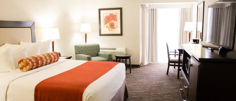 A hotel room with a bed, a desk, a chair, a television, and a framed picture on the wall.