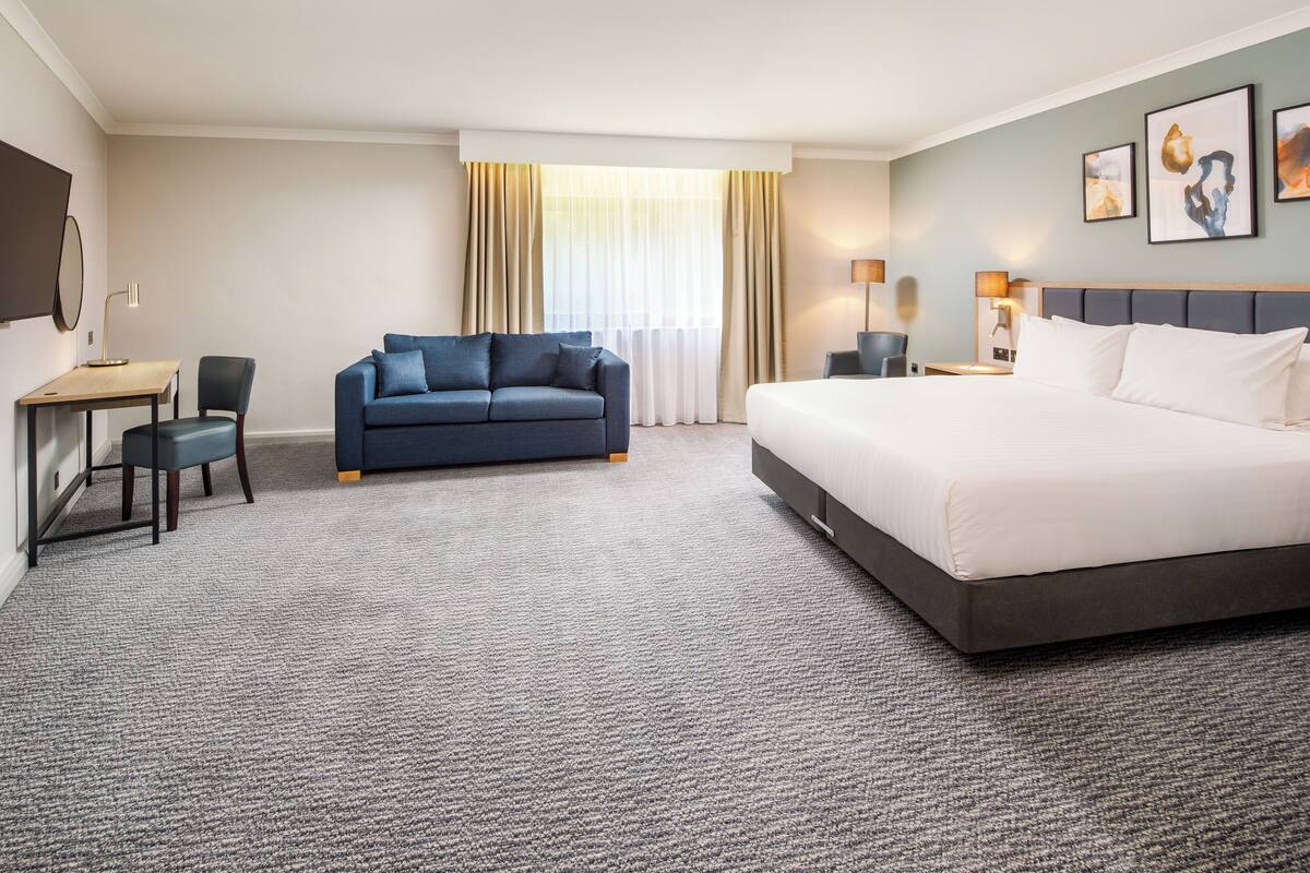 Une chambre d’hôtel avec un grand lit, un canapé, un bureau et une chaise.
