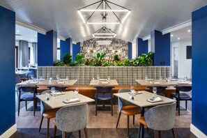 Un restaurant avec plusieurs tables et chaises, un mur décoré de motifs et un luminaire au plafond.