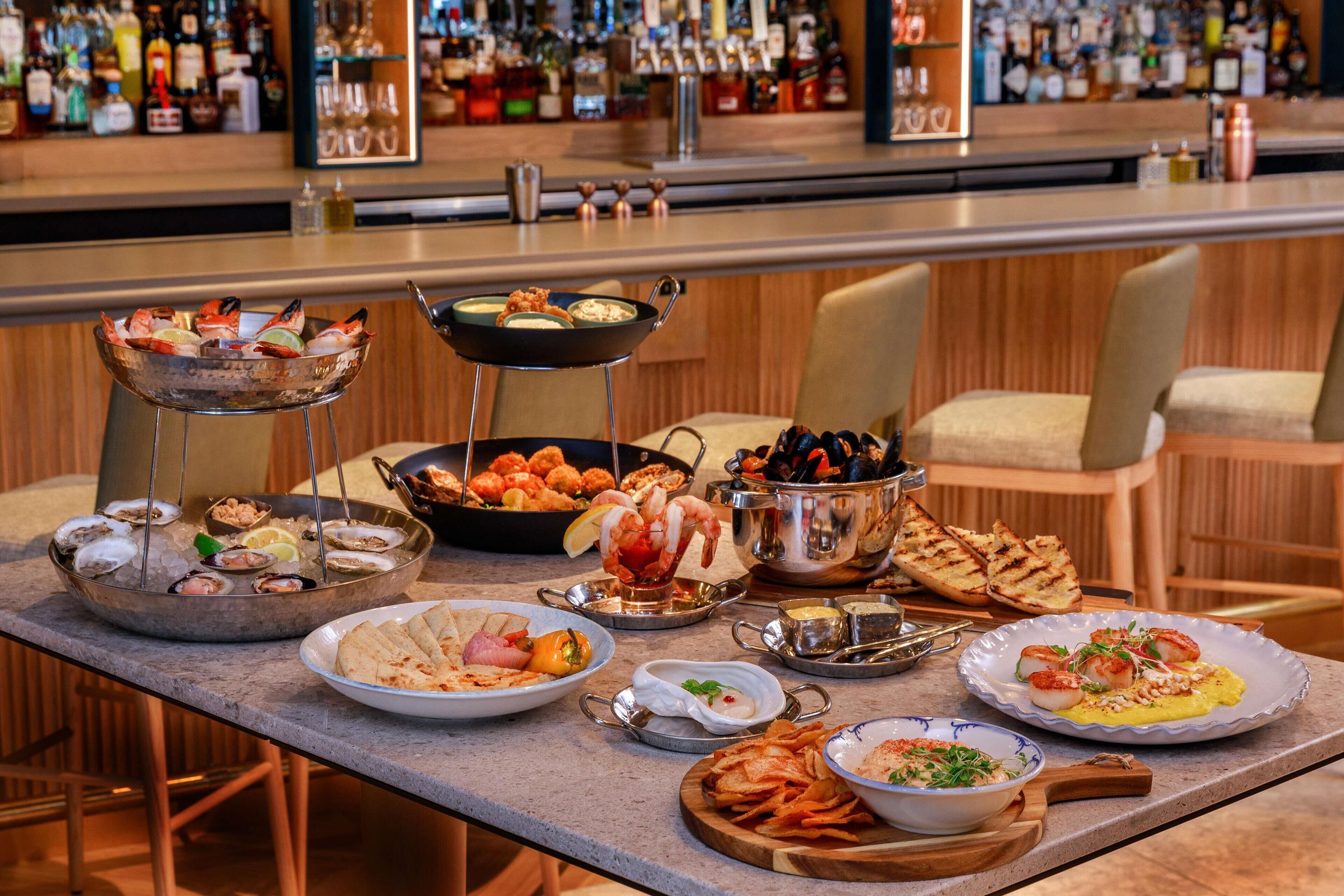 A bar area with various seafood dishes, a selection of drinks, and a bar counter.