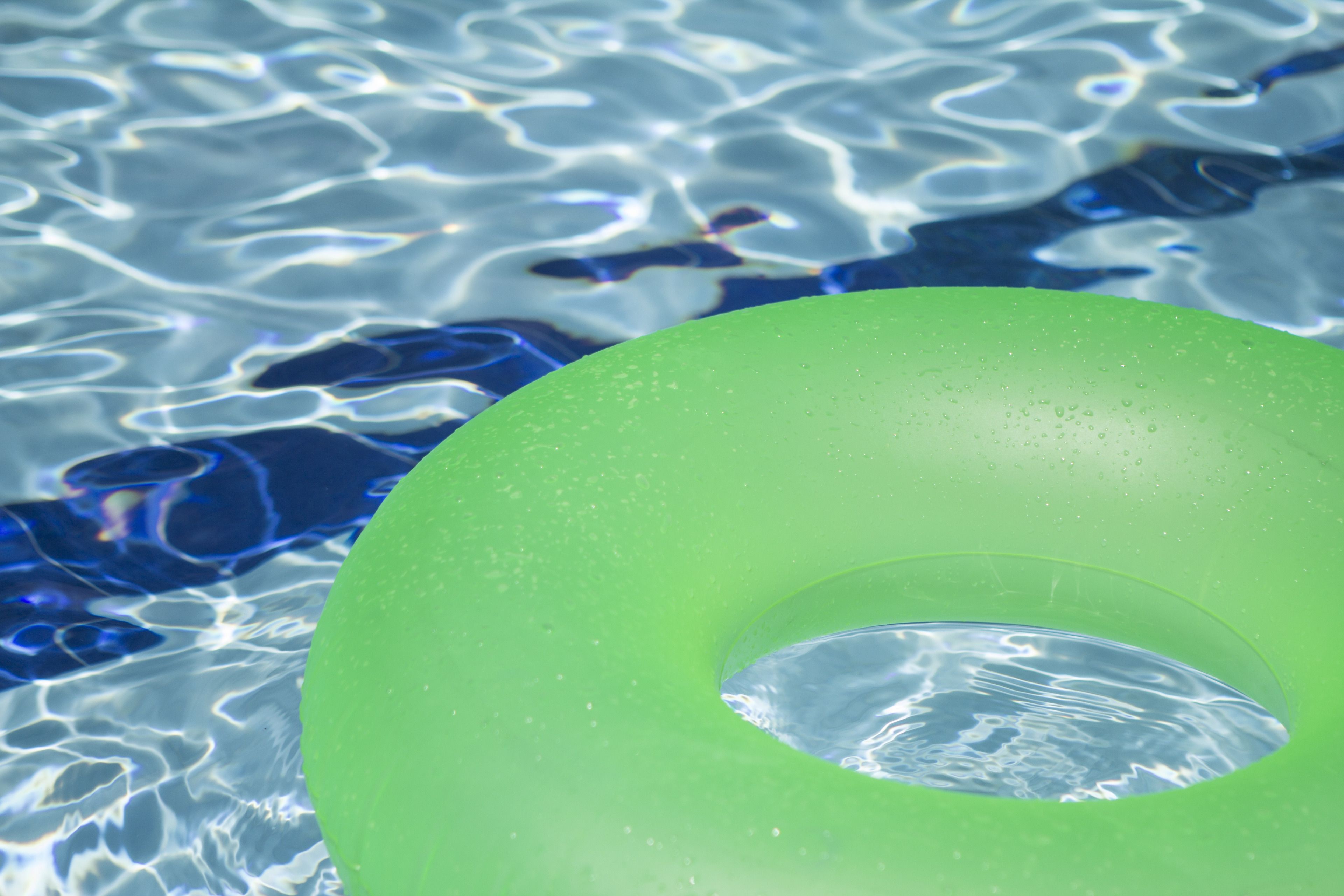 A green inflatable ring in clear water.