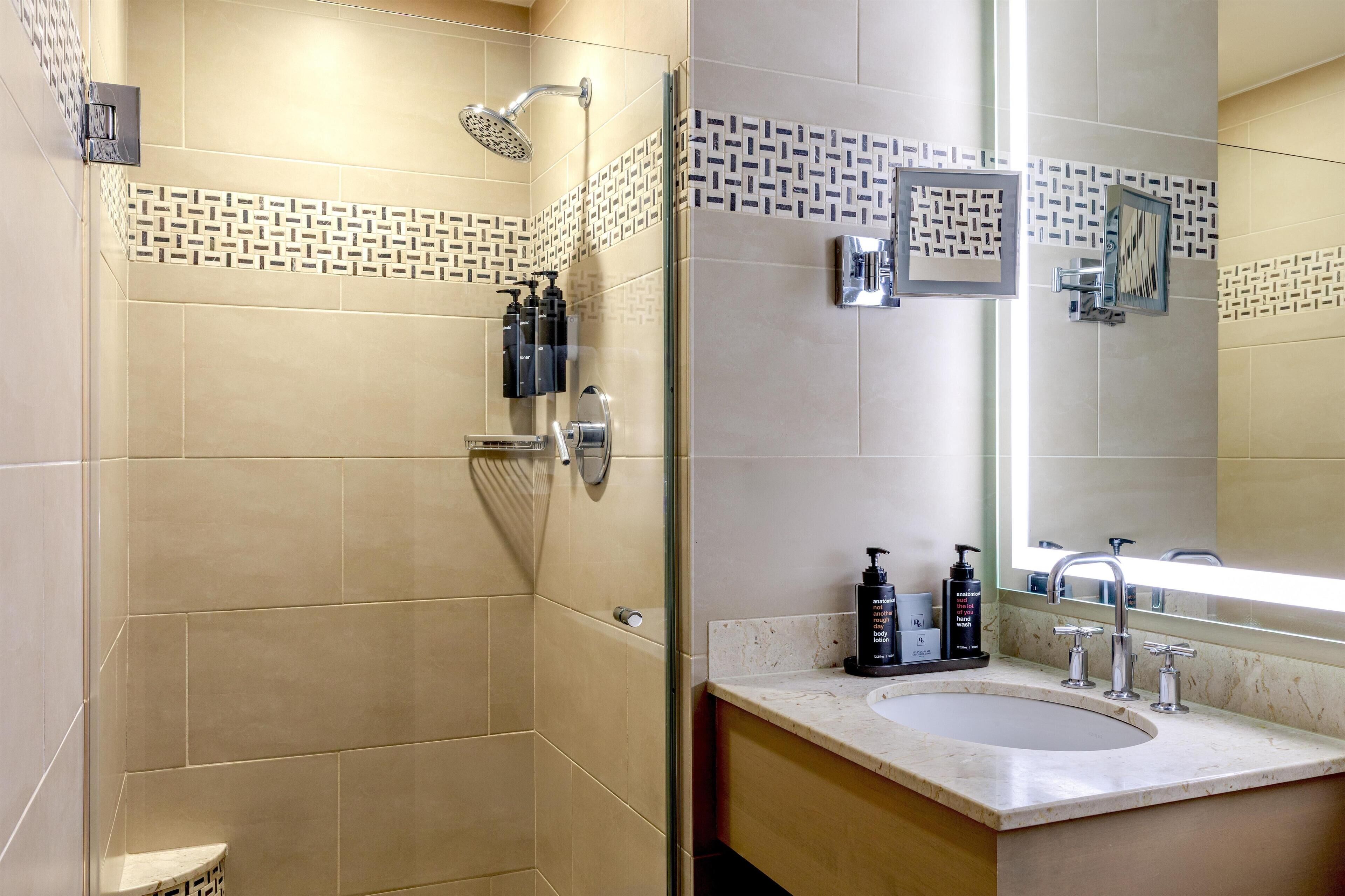 Un baño moderno con ducha, lavamanos y un espejo grande.