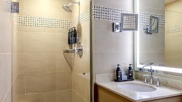 Un baño moderno con ducha, lavamanos y un espejo grande.