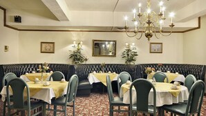 Comedor con asientos tipo cabina y mesas redondas, cada una con mantel y sillas.