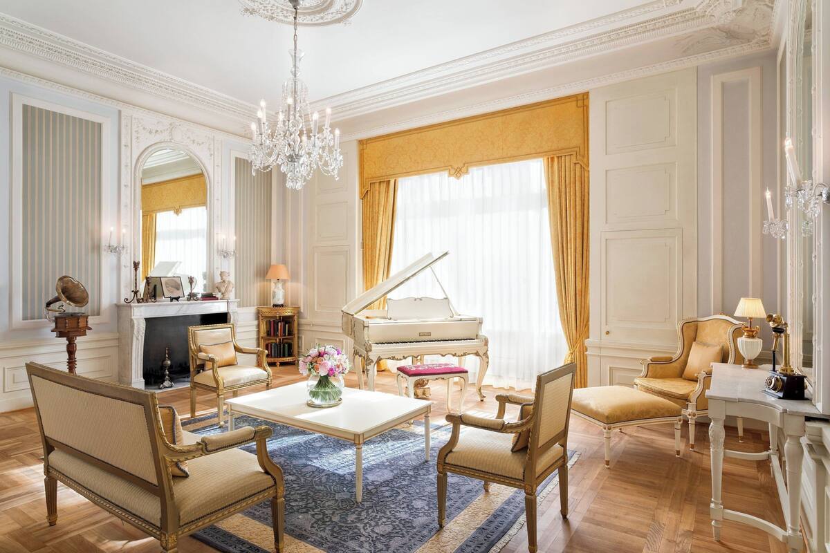 A grand living room with a grand piano, elegant furniture, and a chandelier.