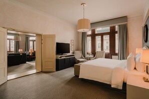 A hotel room with a bed, a desk, a chair, a television, and a large window with curtains.