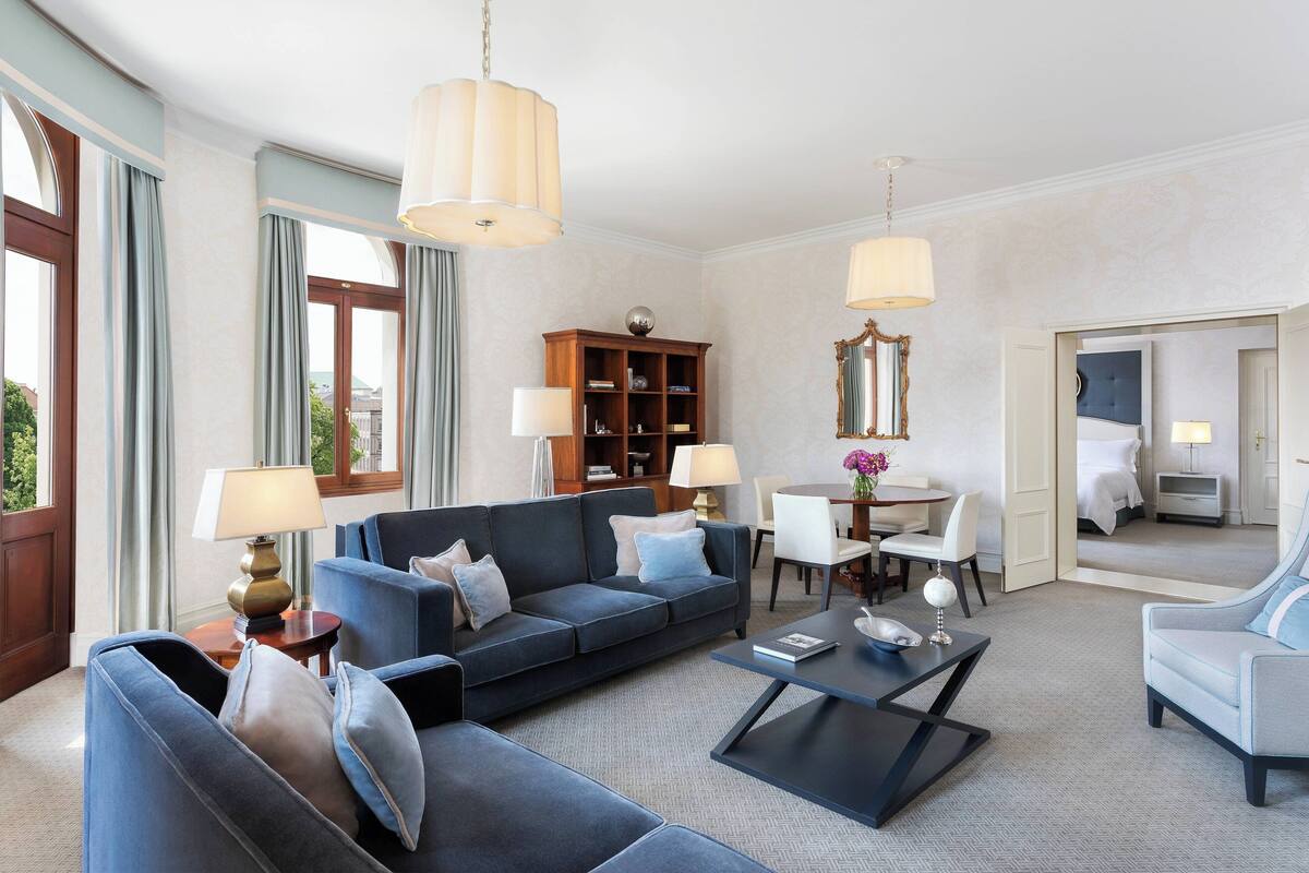 A modern living room with a sofa, armchairs, a coffee table, and a bookshelf.