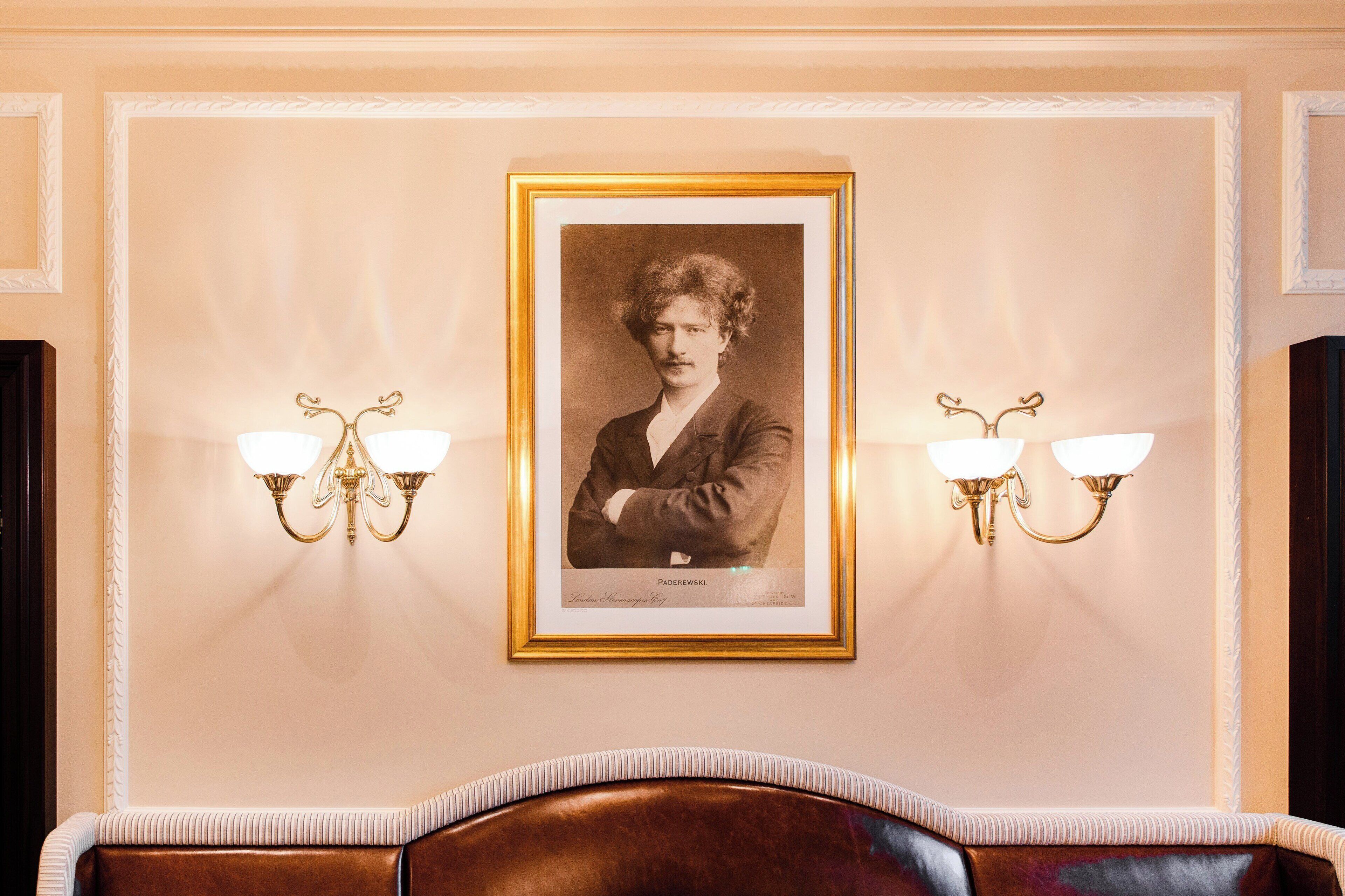 Een ingelijste foto aan een muur, met twee wandlampen.