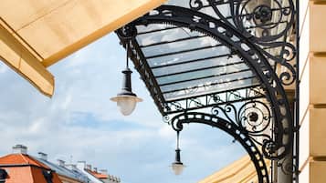 A covered outdoor area with a metal canopy, a street with pedestrians, and buildings in the background.