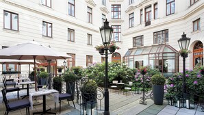 Ein Innenhof mit Außenbestuhlung, Blumentöpfen und einem Gebäude mit Glasdach.