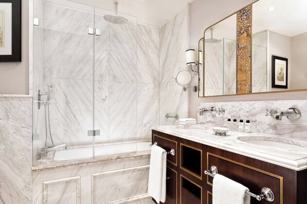 Une salle de bain moderne dotée d’une douche à parois de verre, d’un meuble-lavabo en marbre avec deux vasques et d’un grand miroir.