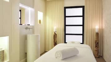 Une chambre d’hôtel avec un grand lit, une table de chevet, un miroir, une fenêtre avec des rideaux et un luminaire fixé au mur.