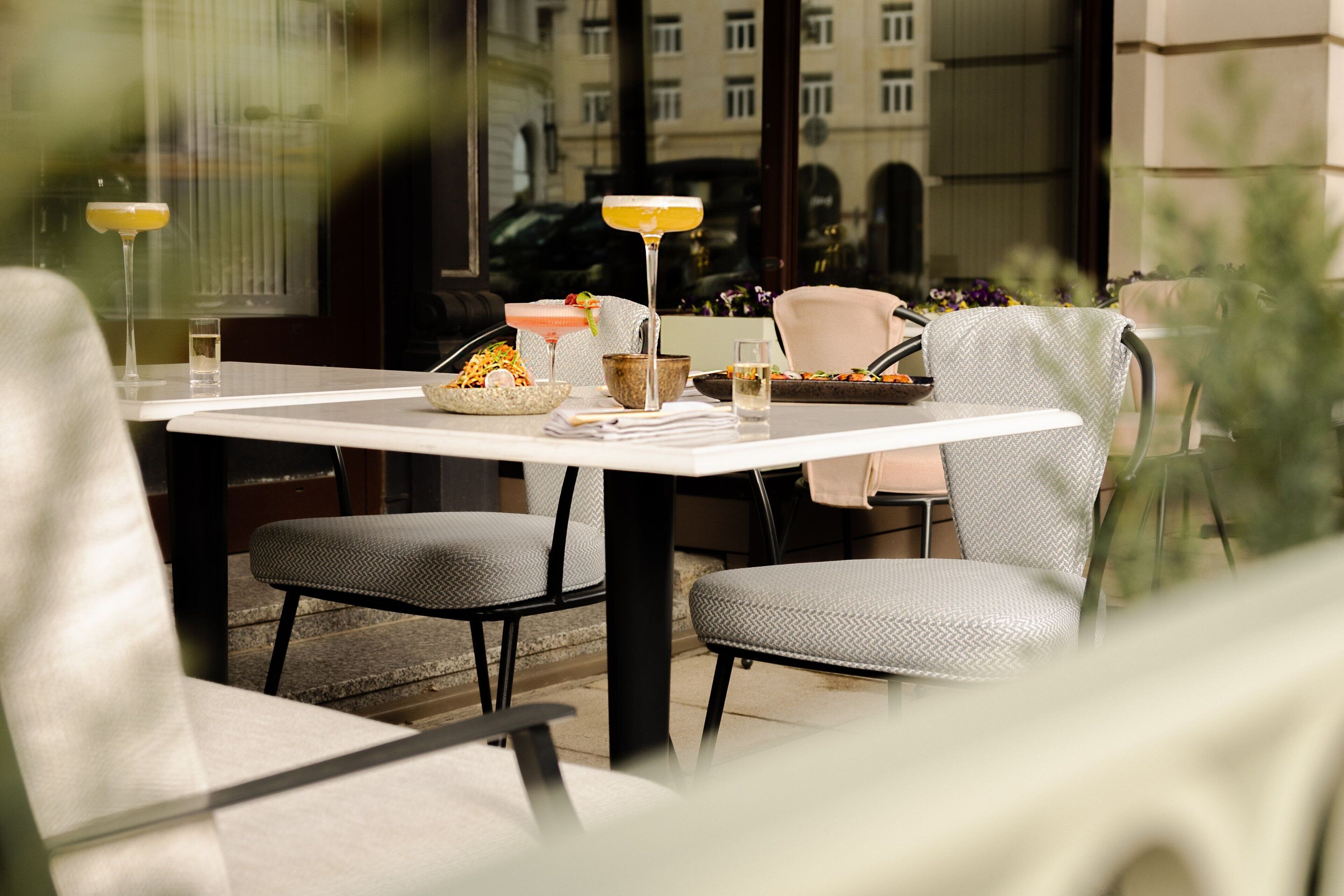 A dining area with a table set for two, featuring a glass of drink, a bowl of snacks, and a small plate.