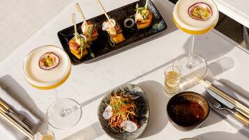 A dining table with a variety of dishes, including skewered appetizers, a bowl of salad, and a glass of wine.