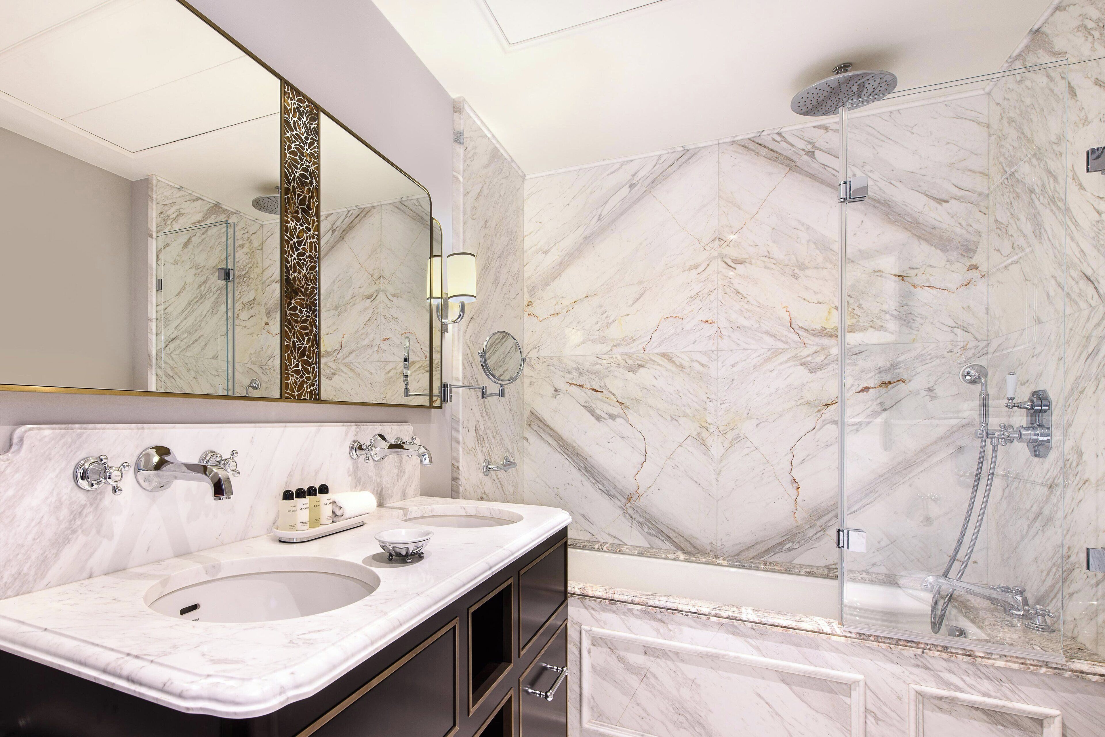Un baño moderno con dos lavamanos, un espejo grande y cabina de ducha con paredes de vidrio.
