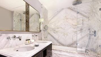 Un baño moderno con dos lavamanos, un espejo grande y cabina de ducha con paredes de vidrio.