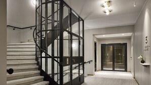 Un interior moderno con una escalera de caracol, una puerta de cristal y un suelo de mármol.