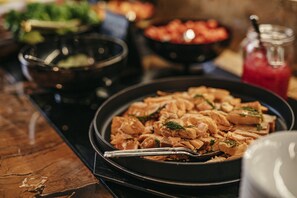 Een eettafel met diverse gerechten, waaronder een saladeschaal, een fruitschaal en een bord eten.