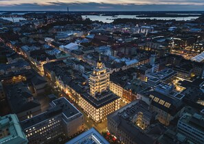 Een stadsgezicht in de schemering met een opvallend historisch gebouw met een toren en meerdere ramen.