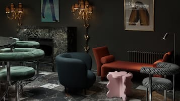 A modern living room with a fireplace, green bar stools, a blue armchair, an orange sofa, and a pink ottoman.